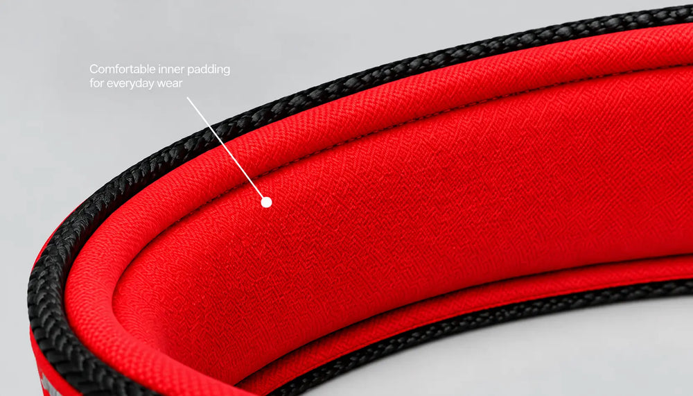 Close-up of a red padded strap or belt with a black braided edge, featuring an inset callout pointing to the comfortable inner padding.