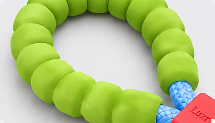A lime green segmented beaded bracelet with a blue braided cord connector and a red plastic tag featuring the brand name LUXE.