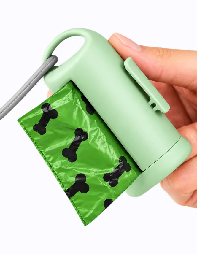 LuxryPaw bone-shaped light green dog waste bag dispenser with a green bag featuring black bone patterns attached to a leash