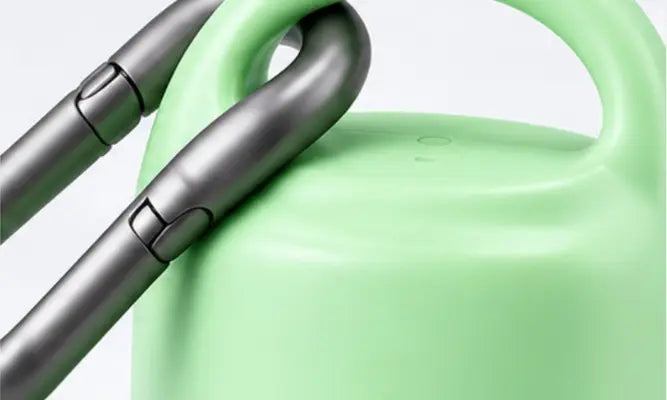 Close-up of a light mint green container or bottle with a dark gray metallic handle or strap attached, shown against a clean white background.